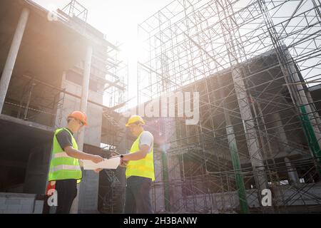 Engineer discussing with foreman about project in building construction site. Stock Photo