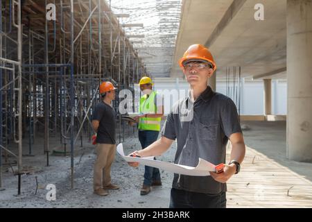 Architect, Engineer, Contractor, or Construction manager holding blueprint standing with a group at a construction site. Stock Photo