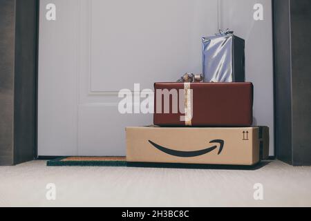 Boxes with Amazon logo in front of the house door. Order on delivery. Christmas gifts in cardboard box on the doormat. Amazon Prime priority delivery. Stock Photo