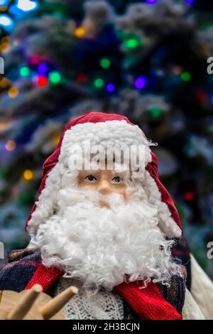 Christmas decor skiing santa in cable knit sweater in front of bokeh flocked Christmas tree - selective focus Stock Photo