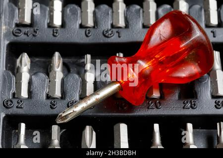 The screwdriver has a red handle and there are several bits Stock Photo