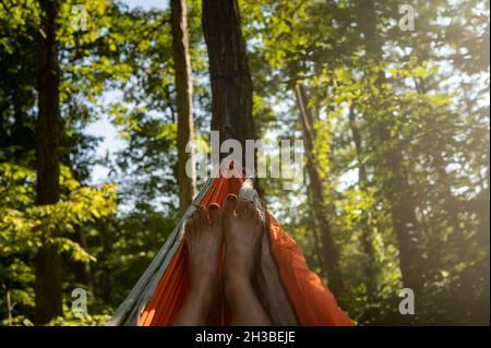 POV shot of woman's painted toe nails in hammock in a green forest Stock Photo