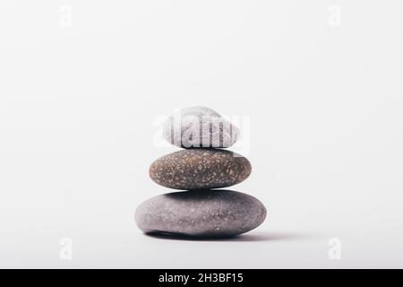 Stack of stones on white background, zen composition of gray pebbles, close-up Stock Photo