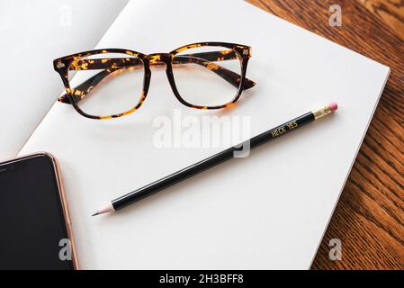 Glasses, iPhone, and Motivational Pencil on a Blank Notebook Stock Photo