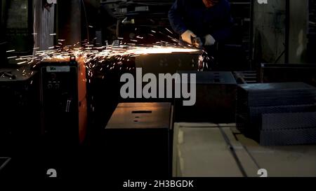 Man grinds a metal sheet. Clip. Grinding machine on work and spark movement in the automotive parts industry Stock Photo