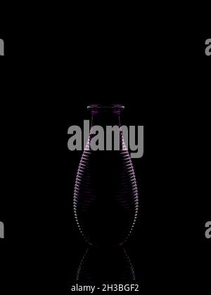 Outline of a ribbed purple glass vase on black background Stock Photo