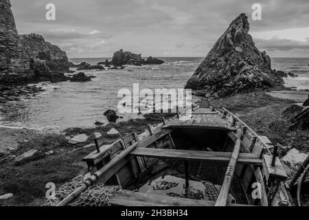 Grayscale shot of an island with a fishing boat on the shore Stock Photo