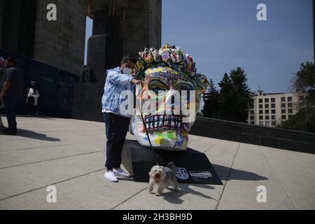 A  man with his dog poses  in front of a monumental skull during the Frida Kahlo Skulls exhibition at Revolution Monument as part of Day of the Dead Mexican celebrations. On October 26, 2021 in Mexico City, Mexico. (Photo by Ismael Rosas/ Eyepix Group) Stock Photo