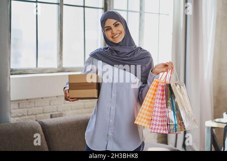 Gorgeous Muslim lady with gift bags, cardboard box and a smile on her face Stock Photo