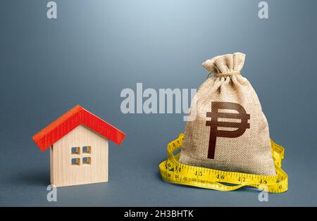 House and a philippine peso money bag. Property real estate valuation. Building maintenance. Mortgage loan. Calculation of expenses for purchase, cons Stock Photo