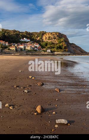 The steeply raked white-painted cottages of Runswick Bay at low-tide in the North York Moors National Park, Yorkshire, England Stock Photo