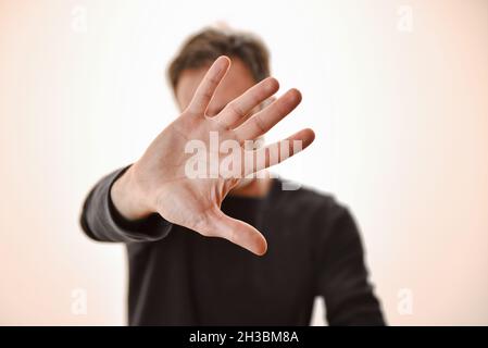 Man hiding with gesture of protection for social fear with outstretched arm and palm in front of the face Stock Photo