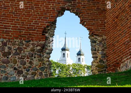 ancient stone and red brick castle ruins with white church towers in the background Stock Photo