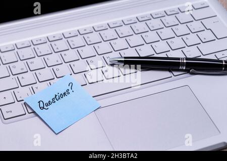 The photo shows a note with the text questions on a notebook computer Stock Photo