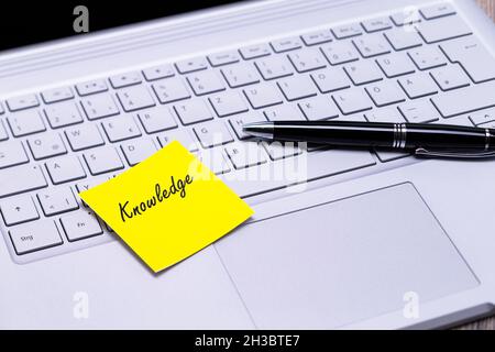 The photo shows a note with the text knowledge on a notebook computer Stock Photo