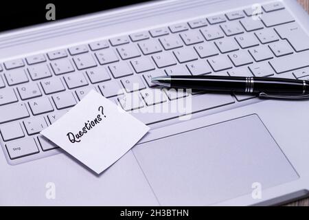 The photo shows a note with the text questions on a notebook computer Stock Photo