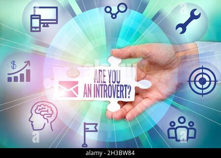 Hand writing sign Are You An Introvertquestion. Business concept person who tends to turn inward mentally Hand Holding Jigsaw Puzzle Piece Unlocking Stock Photo