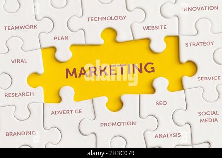 White details of puzzle with the text 'Marketing' on yellow background. Stock Photo