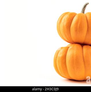 Two orange pumpkins on top of each other on white background. Copy space on the left hand side of pumpkins Stock Photo