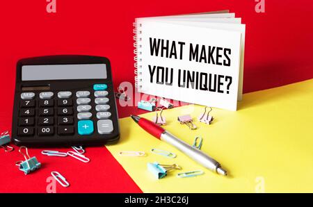 The question is what makes you unique is written on a notebook that stands on a red and yellow background. Stock Photo