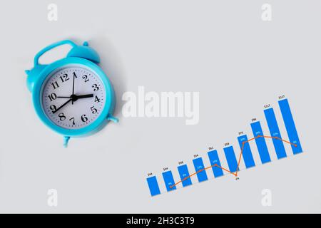 Blue alarm clock and growth graph isolated on white background Stock Photo