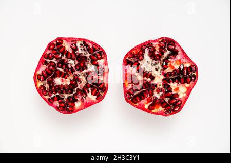 Table top view of two ripe, juicy pomegranate halves against white background Stock Photo
