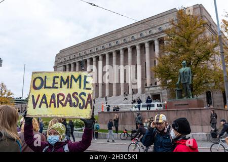 Olemme vaarassa. Climate change protestor with cardboard sign in front of Parliament Building in Helsinki, Finland. Stock Photo