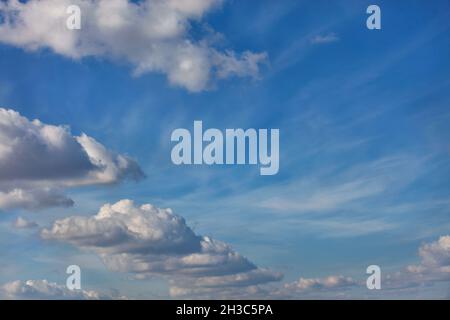 Lush white clouds float in a rhythmic semicircle across the bright blue sky. Stock Photo