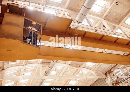 Joyful worker standing in operator cabin of overhead crane Stock Photo