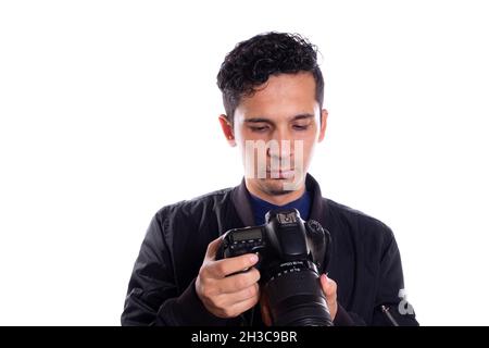 Man looking at his professional camera, isolated on white background. Young adult using a digital camera. Stock Photo
