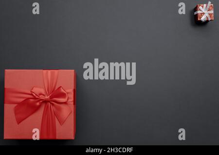 Big and small red gift boxes in different corners on dark background. Top view Stock Photo