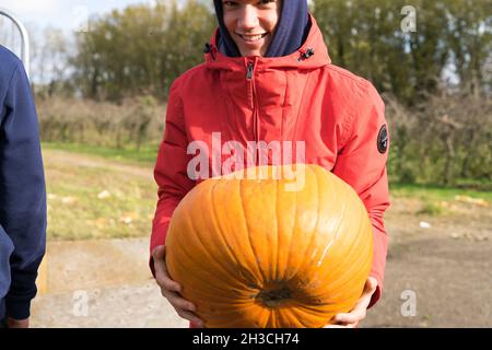 a man holding a  massive pumkin at local Farm field Kent England UK Stock Photo