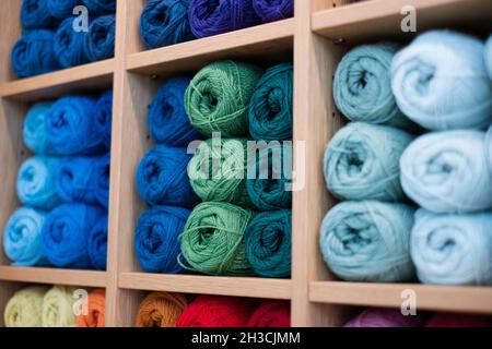 Colorful balls of yarn in shop display. Selective focus on green threads. Multi-color wool. Handcraft and handmade background concept. Stock Photo