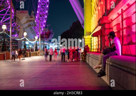 LONDON - SEPTEMBER 14, 2021: Colourfully lit night time scene on The Queen's Walk, Southbank between The London Eye and County Hall Stock Photo