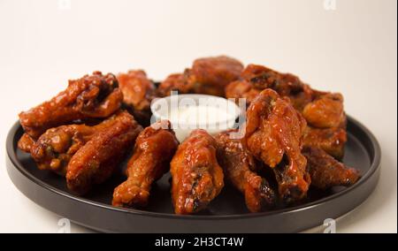 Closeup shot of hot and spicy buffalo chicken wings on a white background with blue cheese dip Stock Photo