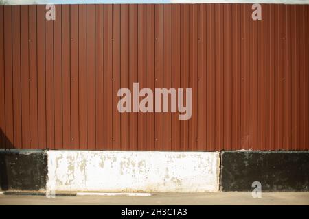 White and black curb on the background of a brown fence. Obstacle at the construction site. Safety from construction works. Stock Photo