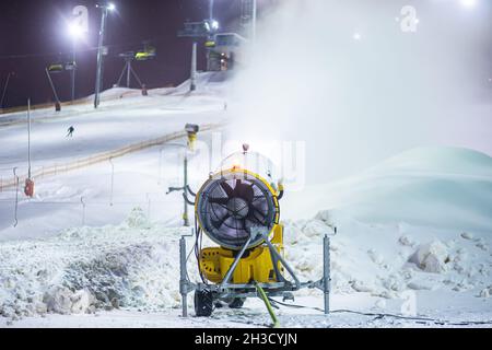 Snow cannon gun, artificial snow making machine on the slopes of a ski  resort, ski lift and piste Stock Photo - Alamy