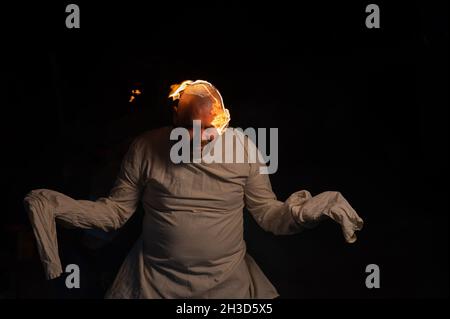 Bald man in a straitjacket with a burning head on a dark background. Stock Photo