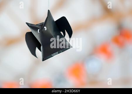 Origami bat made of black paper hanging on a rope for Halloween decorations. Dark paper ghost Halloween party concept origami paper bat. The figure of Stock Photo