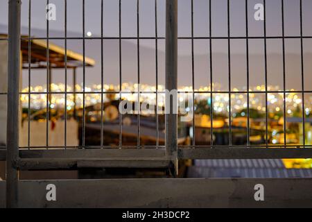 City lights behind the metal fences at night during full moon. Bursa city view from lowland to ulu mountain (uludag) and many lights beyond the fences Stock Photo