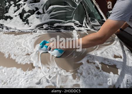 Car wash, car cleaning service, a man washes the hood of a car with a sponge with foam Stock Photo
