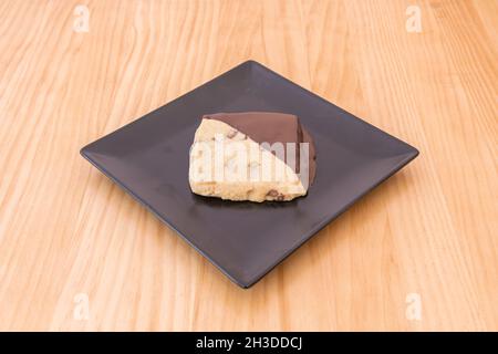 Square cookie of black and white chocolates with nuts on wooden table Stock Photo