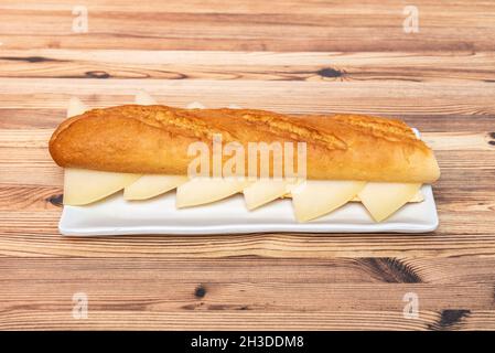 Baguette bread sandwich with chopped Manchego cheese on white plate Stock Photo