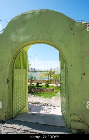 Metallic door painted green as well as the stone wall that supports it. Muslim architecture with entrance to a patio and viewpoint to the river Stock Photo