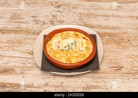 Gnocchis of mashed potatoes cooked with nutmeg and four cheeses with basile in a clay pan Stock Photo