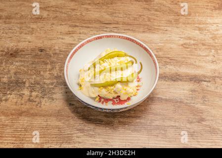 bowl with Russian salad with boiled egg, mayonnaise sauce and piparras on top Stock Photo