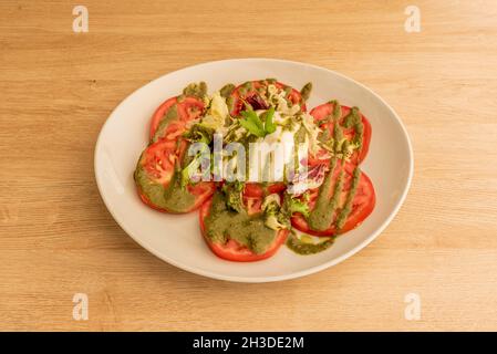 burrata cheese salad with tomato slices and ratatouille sauce with lettuce and parsley Stock Photo