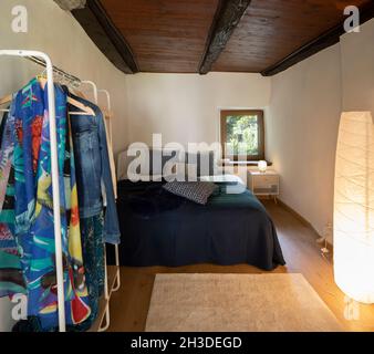 Front view bedroom with double bed, bedside table with a lamp above and a wardrobe on the left. There is a small window with a view of nature. Nobody Stock Photo