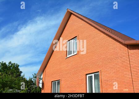 Modern red brick house construction. Brick house facade building with metal roof. Stock Photo