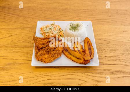 Venezuelan chicken schnitzel with fried plantain, coleslaw and cooked white rice Stock Photo